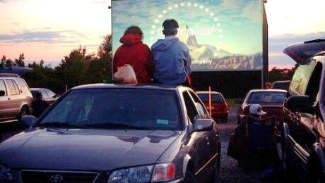 auto vew drive in theater with people sitting on top of car in the 90s