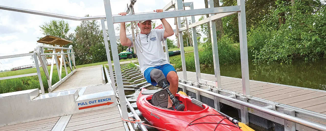 Man getting on a kayak that is disabled